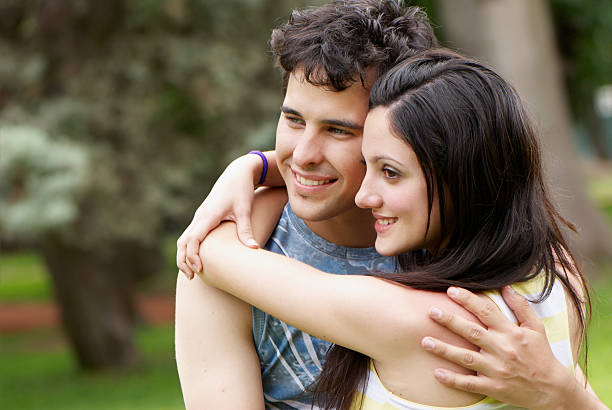 istock couple portrait outdoors smiling with a green background 104685605