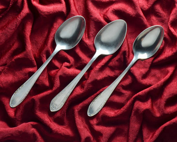 istock A set of three metal spoons on a red silk tablecloth. Top view. 1046860154