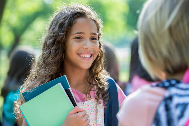 istock Beautiful mixed race student smiles while talking to school friend 1046865354