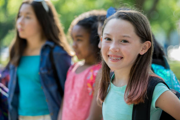 istock Cute elementary student with braces waits with friends outside school 1046867122