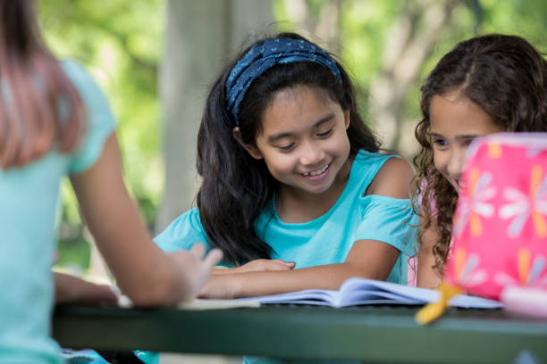 istock Asian girl reading homework assignment with classmates 1046867406