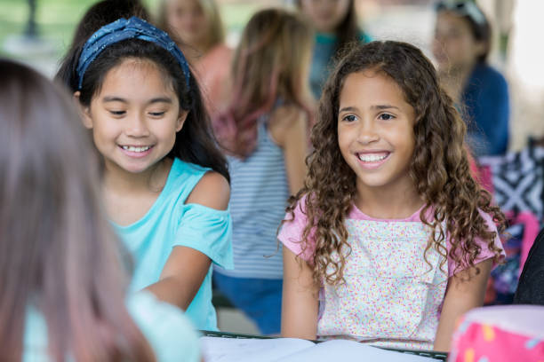 istock Adorable diverse elementary girls reading homework assignment together 1046867408