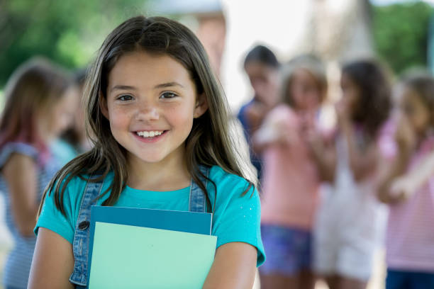 istock Happy elementary age girl smiles while standing outside school 1046867486