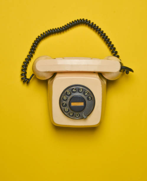 istock A rotary retro phone on a yellow background. Top view. 1046869818