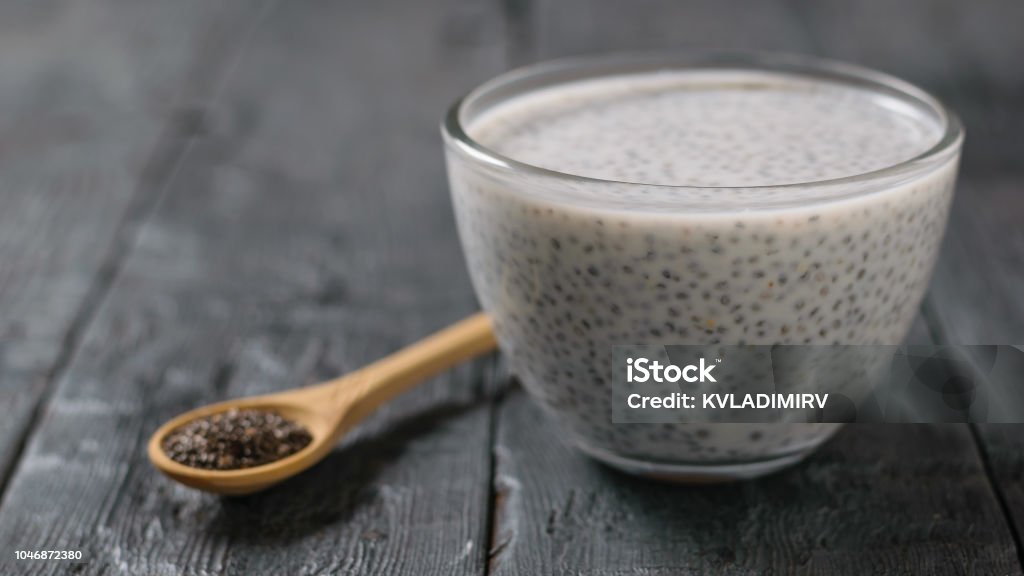 Glass bowl with milk Chia seed pudding on dark wooden table. Glass bowl with milk Chia seed pudding on dark wooden table. Diet food for weight loss and cleansing the body. Chia seed Stock Photo