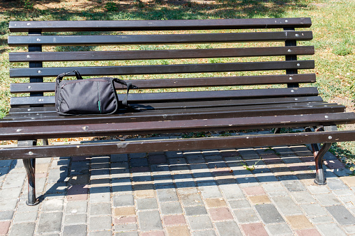 Bag on wooden bench in city park