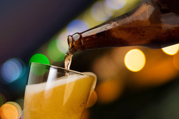 ピンぼけ光夜のガラス瓶から注ぐビールのモーション背景の飲酒アルコールお祝いコンセプト デザイン - beer beer glass drink alcohol ストックフォトと画像
