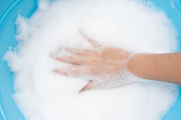 istock Bubble foam with hands female on top view on blue plastic basin background 1046877836