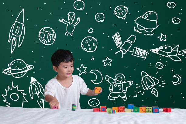 istock Asian kid learning by playing with his imagination about science and space adventure, hand drawn on the green chalkboard, education back to school and discovery concept. 1046888800