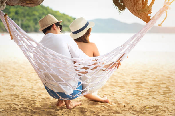 istock Young happy couple relaxing on the beach on a hammock 1046888982