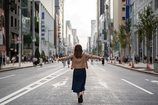 Joyful woman walking on the street with arms open