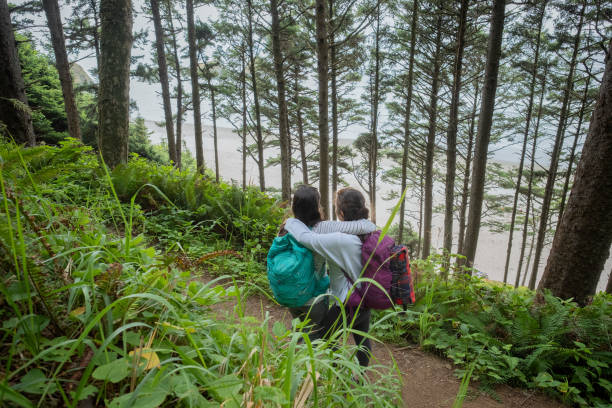 istock Sisters Hugging While Admiring View of Beach from Forest Trail 1046897408