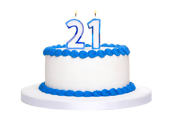 white and blue iced birthday cake with twenty one in candles - 21e verjaardag stockfoto's en -beelden