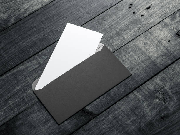 istock Opened black envelope with white invitation or letter mockup inside on wooden table 1046909502