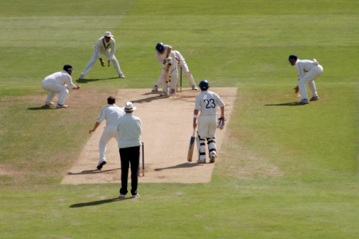 Male cricket team members ready to play cricket together. They are wearing white standing together in a huddle on a sunny day in Northumberland.