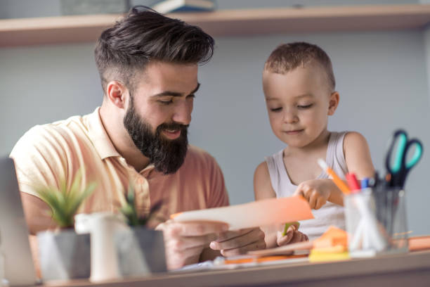 istock Father playing with son at home office 1046917084