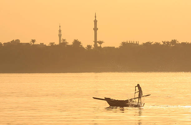 Traditional egyptian fellucas sailing boat on river Nile in silhouette at dusk sunset