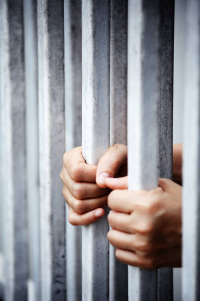 istock hands of prisoner in jail background 1046929124