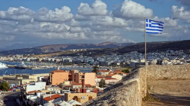 Beautiful view of the coastal town from the old fortress, Crete, Greece. Flag of Greece.