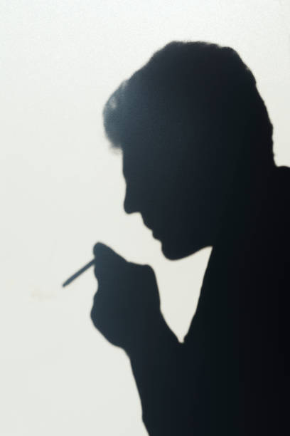 istock shadow of smoking man, young man smoking a cigarette, concept abstract background 1046932120