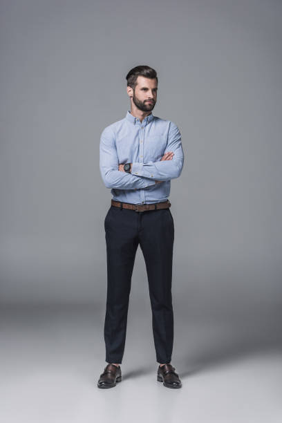 istock handsome confident businessman standing with crossed arms, on grey 1046941020