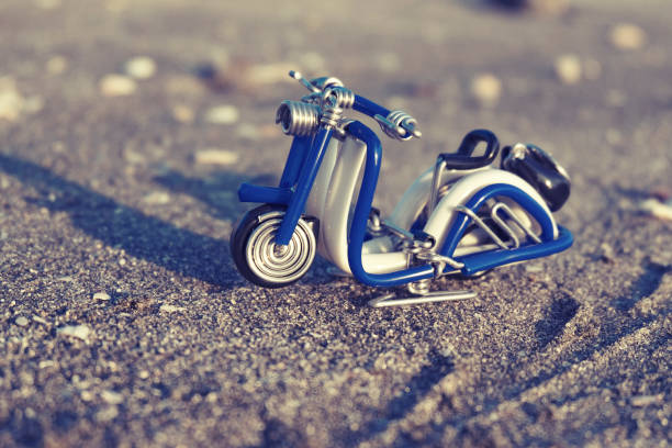 istock travel image concept, wired handcratfed miniature scooter on sandy beach background 1046943744