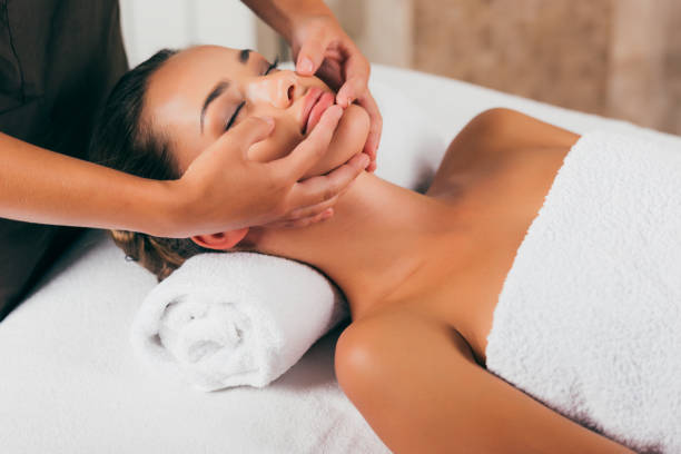 beautiful woman having face massage in spa salon stock photo