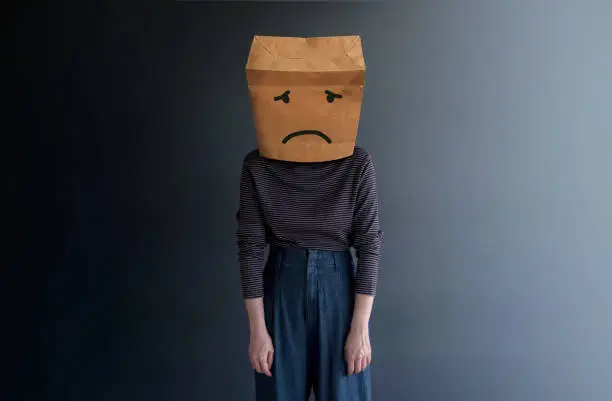 Photo of Customer Experience or Human Emotional Concept. Woman Covered her Face by Paper Bag and present Sad Feeling by Drawn Line Cartoon and Body Language