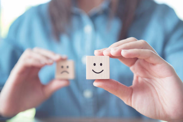 istock Close up hand choose smiley face and blurred sad face icon on wood cube 1046954882