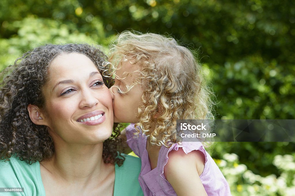 Retrato de menina beijando sua mãe no rosto - Foto de stock de Abraçar royalty-free