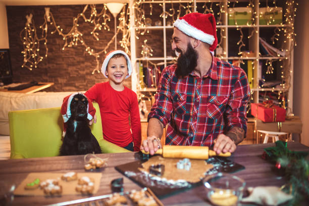 padre, hijo y cachorro haciendo galletas de navidad de pan de jengibre. - sprinkling can fotografías e imágenes de stock