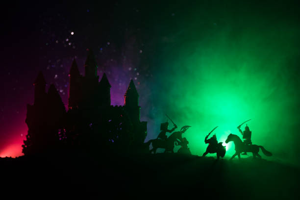 istock Medieval battle scene with cavalry and infantry. Silhouettes of figures as separate objects, fight between warriors on dark toned foggy background with medieval castle. Night scene. Selective focus 1046974398