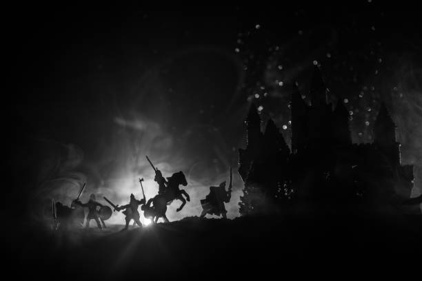 istock Medieval battle scene with cavalry and infantry. Silhouettes of figures as separate objects, fight between warriors on dark toned foggy background with medieval castle. Night scene. Selective focus 1046974408