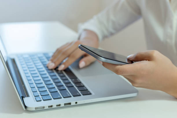 istock Woman holding mobile phone and using laptop 1046983122