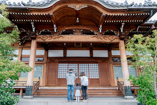 Family of tourists praying at a Japanese Temple. Osaka, Japan. September 2018