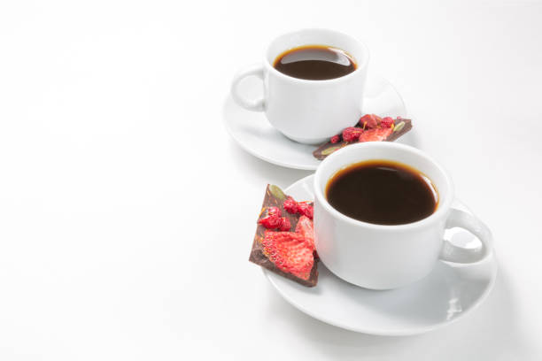 две чашки кофе и шоколад ручной работы с сушеной клубникой и ягодами на белом фоне - two objects cup saucer isolated стоковые фото и изображения