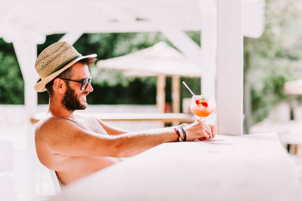 istock Young man enjoying cocktail in a beach bar 1046995324