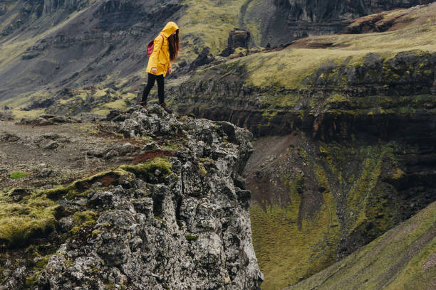 istock young woman looking down from cliff in iceland mountains 1046995570