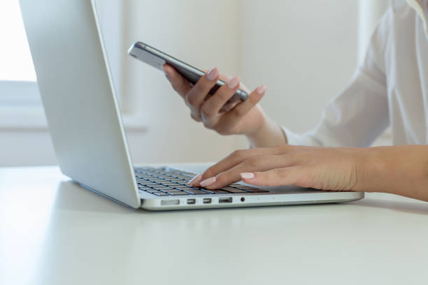 istock Woman using smartphone and laptop 1046998392
