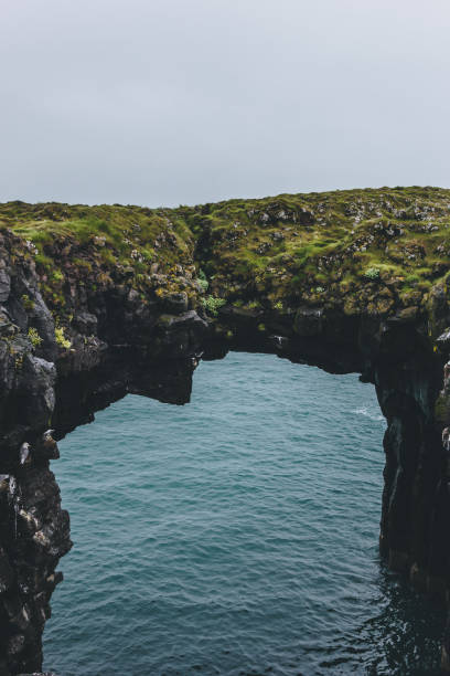 istock mossy cliff in shape of arch with blue ocean on background in Arnarstapi, Iceland 1047000804