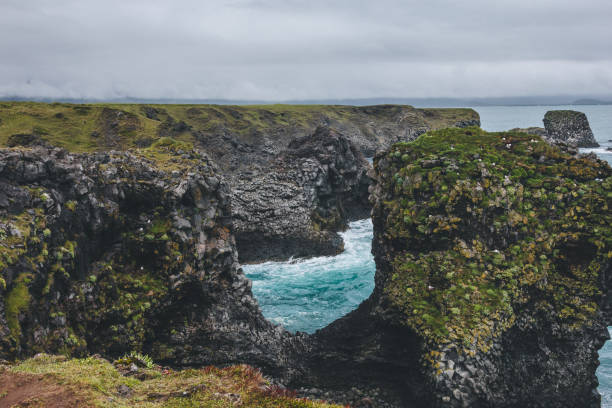 istock beautiful mossy cliffs in front of blue ocean in Arnarstapi, Iceland on cloudy day 1047000856