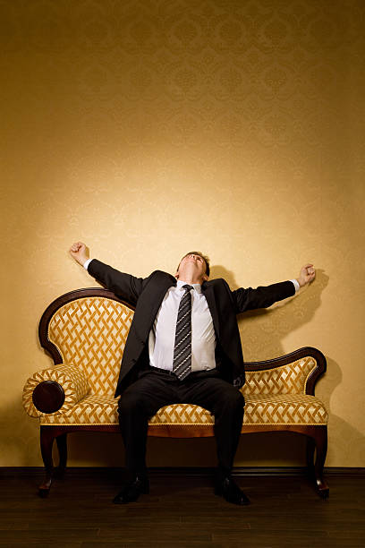 istock Businessman in suit stretches after dream sitting on sofa 104700189