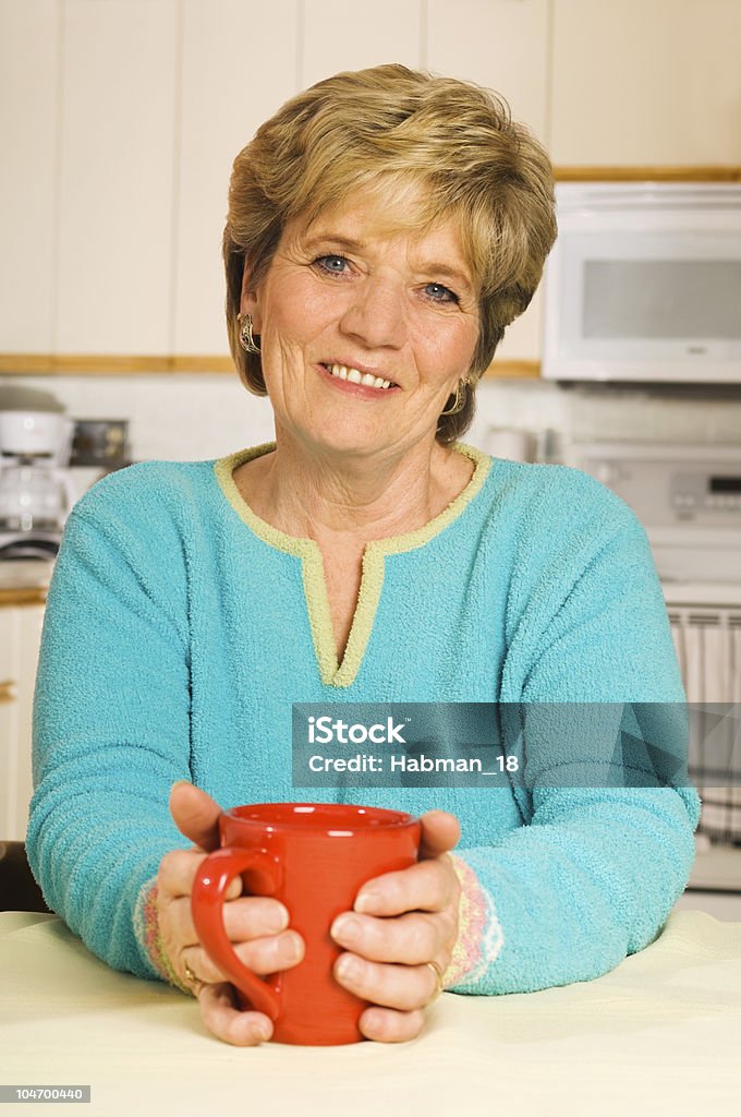 Mujer feliz tiene una taza de café en la cocina - Foto de stock de 60-69 años libre de derechos