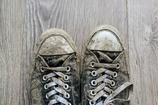 A pair of dirty trainers on wooden flooring