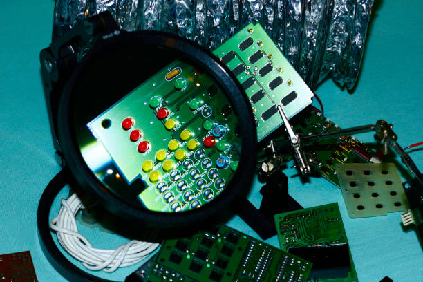 istock Electronic components printed circuit boards with magnifying glass in the foreground. 1047016432