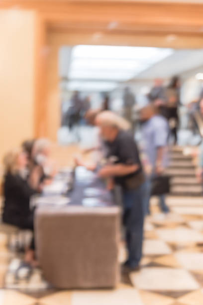 istock Blurry background side view participants at conference check-in table near hotel staircase 1047019884