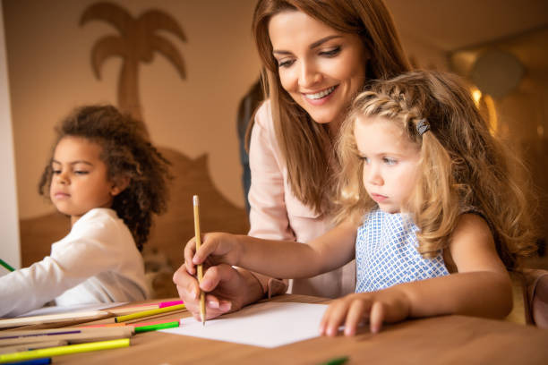 istock happy tutor helping kid drawing in kindergarten 1047023900