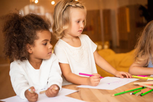 istock adorable multicultural friends drawing together in kindergarten 1047024000