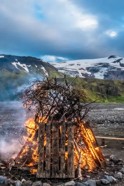 Photo of Ritual bonfire during the summer solstice in the midst of the surreal landscapes of Thorsmork in the Highlands of Iceland. The top of the Eyjafjallajokull volcano can be seen in the background, perhaps as reminder of the theatening power of nature.
