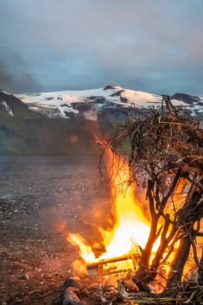 Photo of Ritual bonfire during the summer solstice in the midst of the surreal landscapes of Thorsmork in the Highlands of Iceland. The top of the Eyjafjallajokull volcano can be seen in the background, perhaps as reminder of the theatening power of nature.